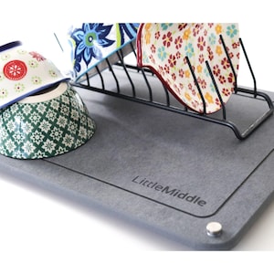 May include: A gray dish drying rack with a black metal frame and a gray, textured base. The base has the words "Little Middle" printed on it. The rack is holding three bowls with floral patterns.