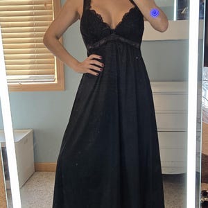 May include: A black maxi dress with a lace-trimmed bodice and spaghetti straps. The dress has a flowing skirt and is made of a soft, lightweight fabric. The dress is suitable for formal or casual occasions.