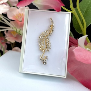 May include: A gold and clear rhinestone nose ring with a leaf design. The nose ring is displayed on a white background.