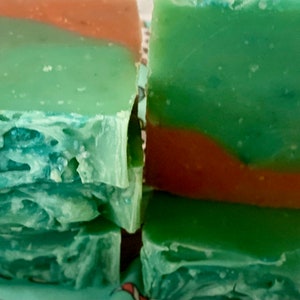 May include: A stack of handmade soap bars with green and orange swirls. The soap bars are made with natural ingredients and are perfect for sensitive skin.