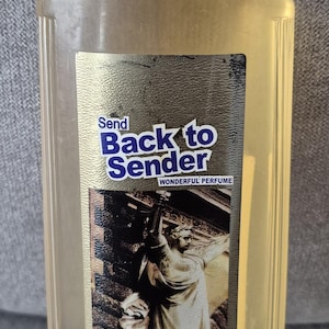 May include: A clear glass bottle with a yellow cap and a gold label. The label says "Send Back to Sender Wonderful Perfume" and features a picture of a statue. The bottle contains 500 ml of liquid.