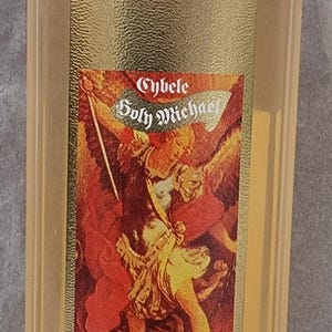 May include: A clear glass bottle with a gold label featuring an illustration of an angel with a sword. The label reads "Cybele Holy Michael" and "500ml 70°".