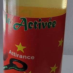 May include: A clear glass bottle with a white cap, containing a yellow liquid. The bottle features a red label with the words "le Activ&eacute;e" in green, yellow stars, and the words "Attirance" and "Succ&egrave;s".