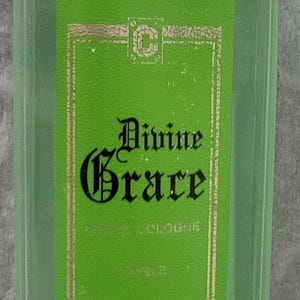 Może przedstawiać: Zielona szklana butelka z czarną zakrętką i zieloną etykietą z napisem "Divine Grace Cologne" czarnymi literami.