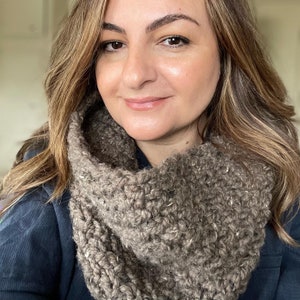 May include: A brown knitted infinity scarf with a textured pattern.