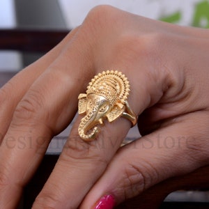 Peut inclure: Bague en or avec un motif d'éléphant détaillé. La tête de l'éléphant est tournée vers l'avant, la trompe levée. La bague est portée à un doigt.