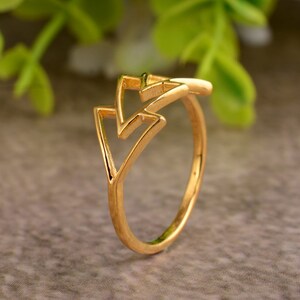 Op de afbeelding: Een gouden ring met een geometrisch ontwerp met twee overlappende driehoeken.