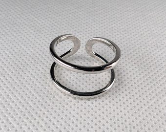 Könnte beinhalten: Ein silberner Ring mit einem Doppelband-Design. Der Ring besteht aus zwei ineinandergreifenden Kreisen.