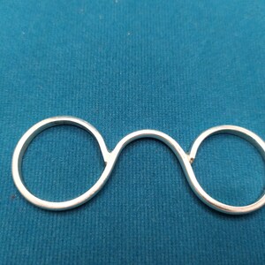 May include: A silver ring with two connected circles, designed to be worn on two fingers.