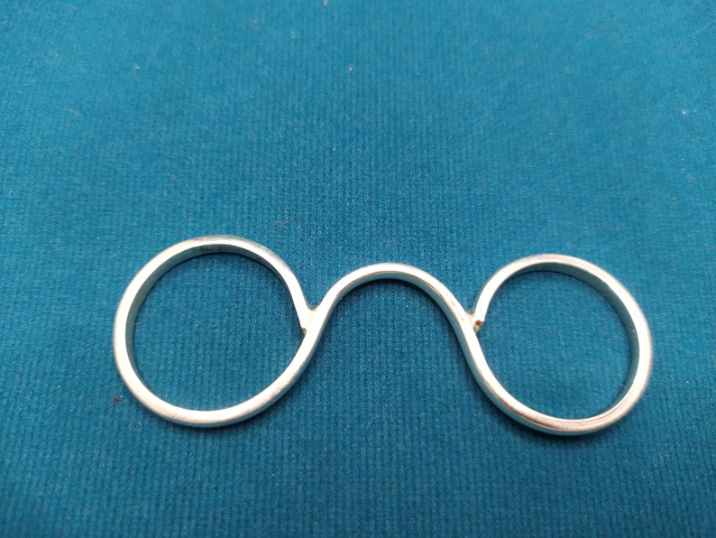 May include: A silver ring with two connected circles, designed to be worn on two fingers.