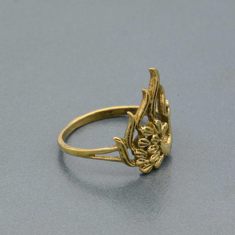 May include: A gold-toned ring with a floral design. The ring is made of metal and has a delicate, intricate design.