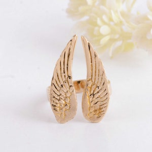 May include: Gold-tone adjustable ring featuring a pair of open wings with a detailed design.