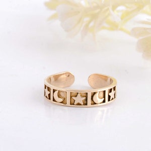 May include: Gold toe ring with a repeating pattern of stars and crescent moons.