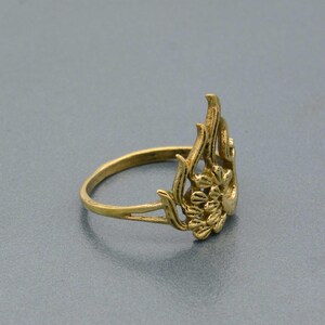 May include: A gold-toned ring with a floral design. The ring is made of metal and has a delicate, intricate design.