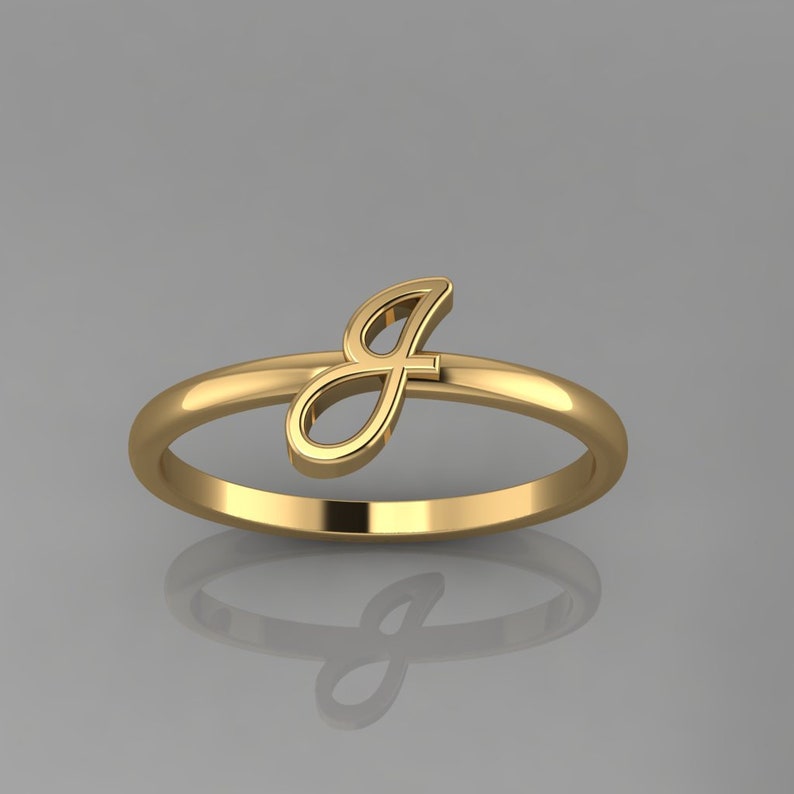 May include: A gold ring with a cursive letter 'J' on the side.