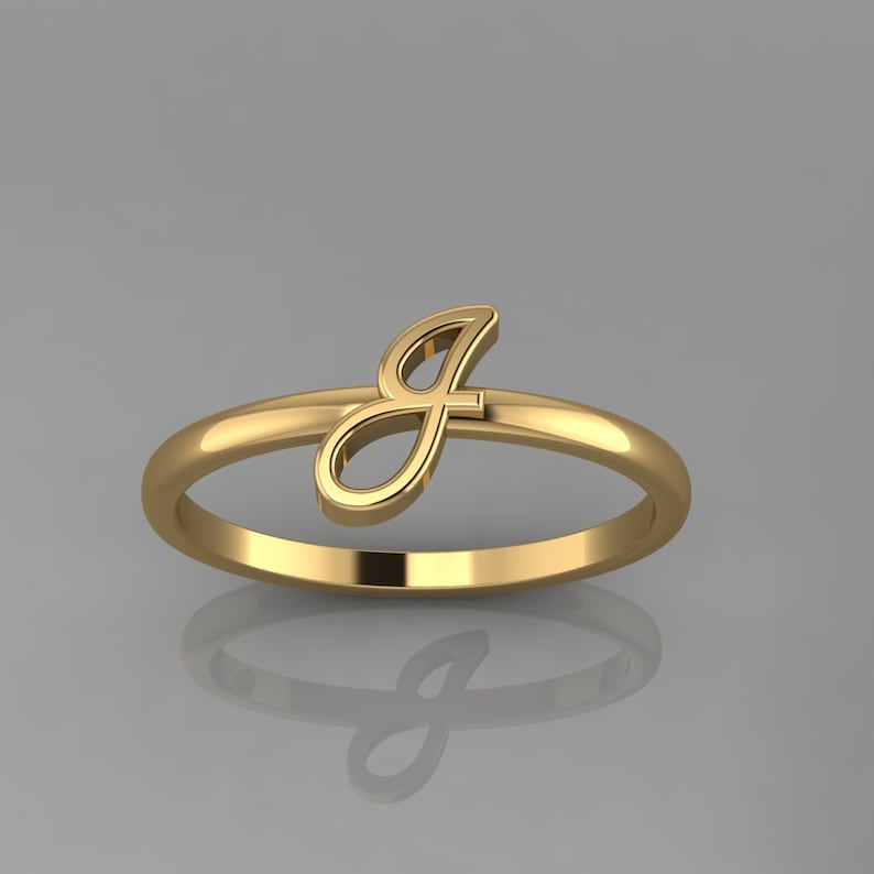 May include: A gold ring with a cursive letter 'J' on the side.