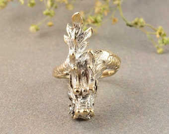 May include: A gold and silver dragon ring with a detailed design. The dragon's head is facing forward with its mouth open.