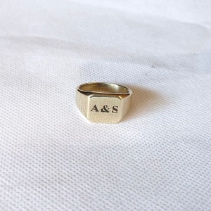 Könnte beinhalten: Ein goldener Siegelring mit quadratischer Oberseite, graviert mit den Initialen "A & S".