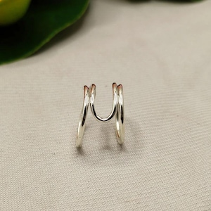 Può includere: Un anello d'argento con un design a triplo anello. L'anello è realizzato con tre anelli intrecciati, creando un look unico e moderno.