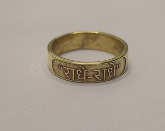 May include: A gold-colored ring with the inscription "राधे-राधे" in Hindi.