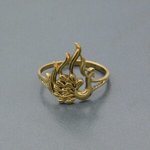 May include: A gold-toned ring featuring a detailed peacock design. The ring is made of metal and has a delicate, intricate design.