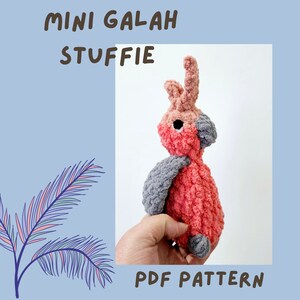 May include: A crocheted stuffed toy bird in the shape of a Galah, a pink and grey Australian parrot. The toy is being held by a hand. The text "MINI GALAH STUFFIE PDF PATTERN" is at the bottom of the image.