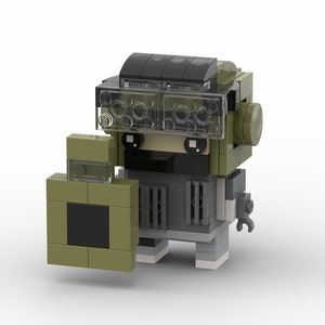 May include: A green and gray Lego minifigure with a shield and a transparent helmet. The minifigure has a black face with white eyes and a black mouth.