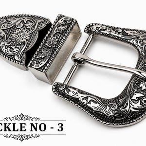 Op de afbeelding: Een zilverkleurige metalen riemgespset met een sierlijk gegraveerd bloemmotief op het frame van de gesp, een bijpassende rechthoekige lus en een puntig uiteinde. De tekst BUCKLE NO - 3 is in het zwart onderaan de afbeelding gedrukt.