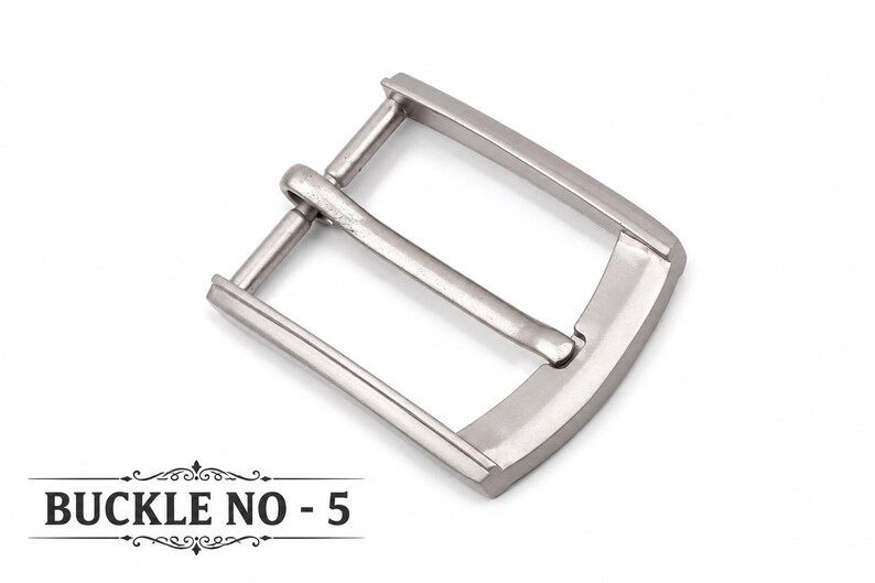 Op de afbeelding: Een zilverkleurige metalen riemgesp met een rechthoekig frame en een centrale doorn. De gesp heeft een gladde, gepolijste afwerking en een gebogen buitenrand. De tekst BUCKLE NO - 5 staat in het zwart linksonder in de afbeelding.