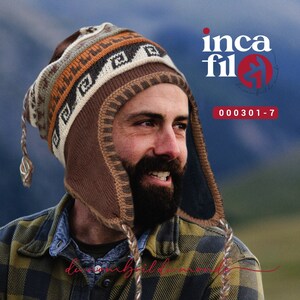 Peut inclure: Un homme portant un bonnet en tricot marron et beige avec un motif géométrique et des rabats d'oreilles. Le bonnet a un long cordon qui pend devant son cou. L'homme sourit et regarde vers la droite. Le bonnet est étiqueté "inca fil" et "000301-7".