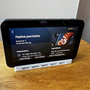 Op de afbeelding: Een screenshot van een recepten-app die een recept voor Feestelijke Porchetta laat zien. Het recept heeft een 5-sterrenbeoordeling en is beoordeeld met 1 van de 5 sterren. Het recept duurt 2 uur en 50 minuten en heeft 594 calorieën. Het recept bevat instructies om de kruidenmix te maken, de steranijs en de buik te roosteren, niet ingesneden. Het recept bevat ook een boodschappenlijst voor 3 kg  ontbeend varkensvlees met schil. De app heeft knoppen om het recept te starten en het recept op te slaan.