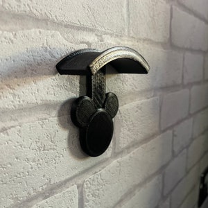 May include: Black 3D printed wall mount with Mickey Mouse ears and a curved top shelf.