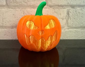 May include: An orange pumpkin with carved-out eyes and a mouth, and a green stem. The pumpkin is a Halloween decoration, with a smiling face. The pumpkin is sitting on a dark surface.