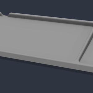 Può includere: Un vassoio lungo e rettangolare di colore grigio chiaro con una finitura liscia e opaca. Il vassoio è diviso in due sezioni distinte, con un'area rettangolare più grande sulla sinistra e un'area quadrata più piccola sulla destra.