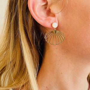 Könnte beinhalten: Goldfarbene Muschel-Ohrringe mit einem weißen Perlenakzent.
