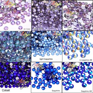 May include: A collection of nine distinct groups of round, faceted rhinestones in various shades of purple and blue, labeled with text including Air Violet, Light Violet, Cyan Vitrail, Fairy Blue, Light Sapphire, Lt. Sapphire AB, Cobalt, Sapphire, and Sapphire AB.