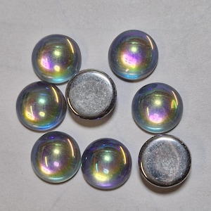 May include: Assortment of iridescent glass cabochons in various shades of blue, green, and purple. The cabochons are round and have a smooth, polished surface. There are also two silver-coloured metal cabochons.