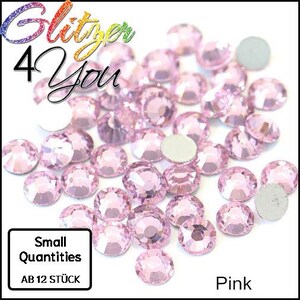 Può includere: Una collezione di strass rosa con un design sfaccettato. L'immagine include il testo "Glitzer 4 You", "Small Quantities", "AB 12 STÜCK" e "Pink". Gli strass sono sparsi su uno sfondo bianco.