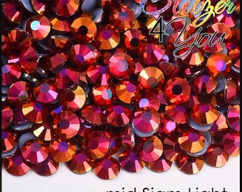 May include: A close-up image of a large quantity of red and orange iridescent rhinestones. The rhinestones are scattered on a white surface. The text "Glitter 4 You" is visible in the upper right corner of the image. The text "mid Siam Light" is visible in the lower center of the image.