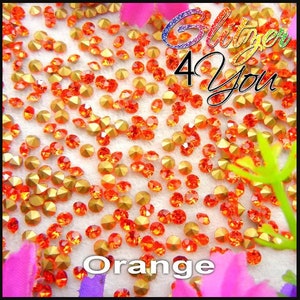 Puede incluir: Cristales de imitación de color naranja con engastes dorados. Los cristales están esparcidos sobre una superficie blanca. El texto "Glitter 4 You" y "Orange" es visible en la imagen.