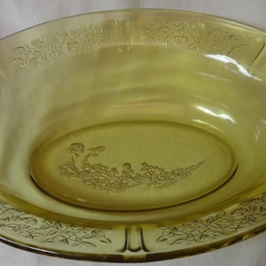May include: A yellow glass oval serving bowl with a floral design etched into the glass.
