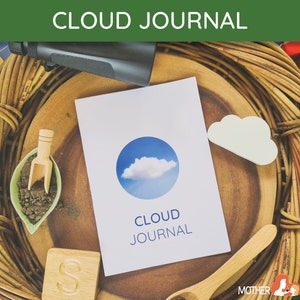 May include: A white journal with a blue circle and a white cloud on the cover. The text "CLOUD JOURNAL" is printed in blue on the cover. The journal is surrounded by various objects, including a wooden tray, a wooden spoon, a small wooden scoop, and a wooden block with the letter "S" on it.