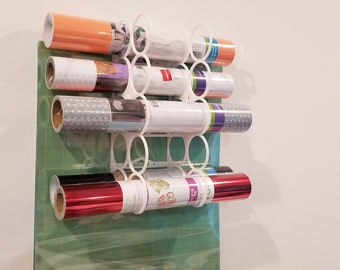 May include: White wall mounted vinyl storage rack with 8 rolls of vinyl in various colors and patterns. The rack is made of plastic and has a circular design.