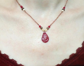 Collier artisanal avec pendentif en argile, motif fleur en relief, ton rouge bordeaux, perles en verre et métal cuivré, chaîne cuivré