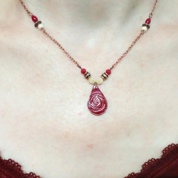 Collier artisanal avec pendentif en argile, motif fleur en relief, ton rouge bordeaux, perles en verre et métal cuivré, chaîne cuivré