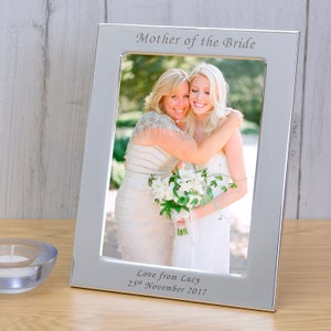 May include: Silver photo frame with a picture of two women hugging. The frame has the text "Mother of the Bride" and "Love from Lucy 25th November 2017" engraved on it.