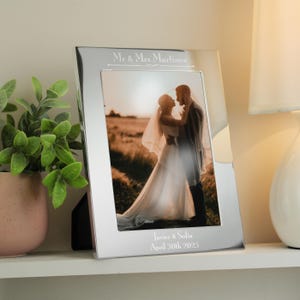 May include: Silver picture frame with a bevelled edge, holding a wedding photo of a couple in a field. The frame is engraved with "Mr. & Mrs. Martinez", "Javier & Sofia", and "April 30th, 2025".