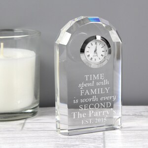 May include: A clear glass clock with a silver face and black Roman numeral hour markers. The clock is engraved with the text "TIME spent with FAMILY is worth every SECOND The Parry's EST. 2015".