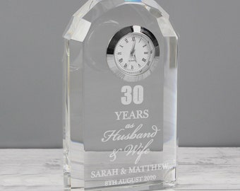 May include: A clear crystal clock with a silver face and black Roman numeral hour markers. The clock is engraved with the text "30 Years as Husband & Wife Sarah & Matthew 8th August 2020".