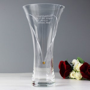 May include: A clear glass vase with a heart-shaped design and a gold accent. The vase is engraved with the text "Congratulations Mr & Mrs Wright 09.12.21 Weston Hall".